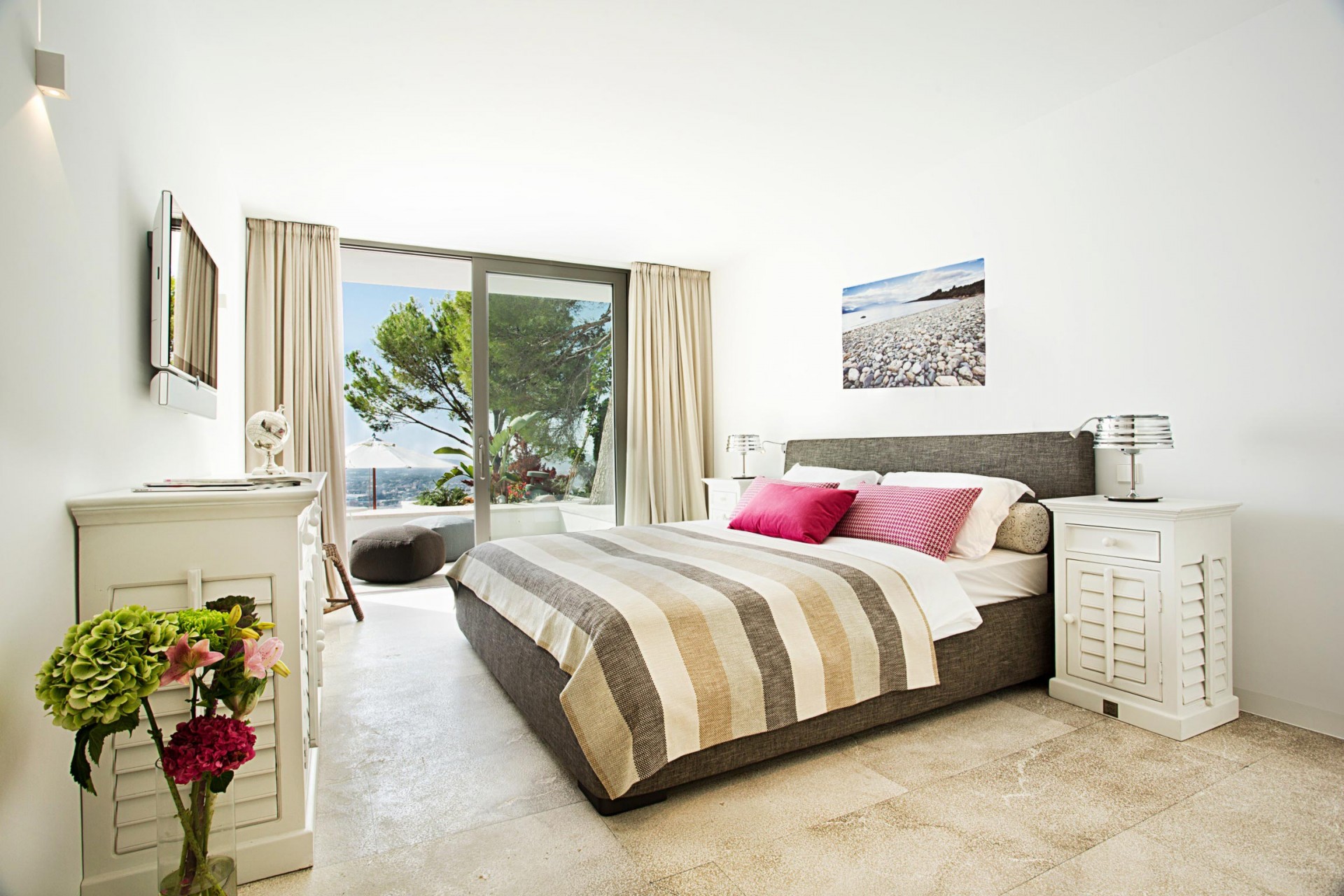 Das in Naturtönen gestaltete Gästeschlafzimmer der Villa Las Brisas. Durch die geöffnete Glastür betritt man den Balkon mit Blick auf das Meer.